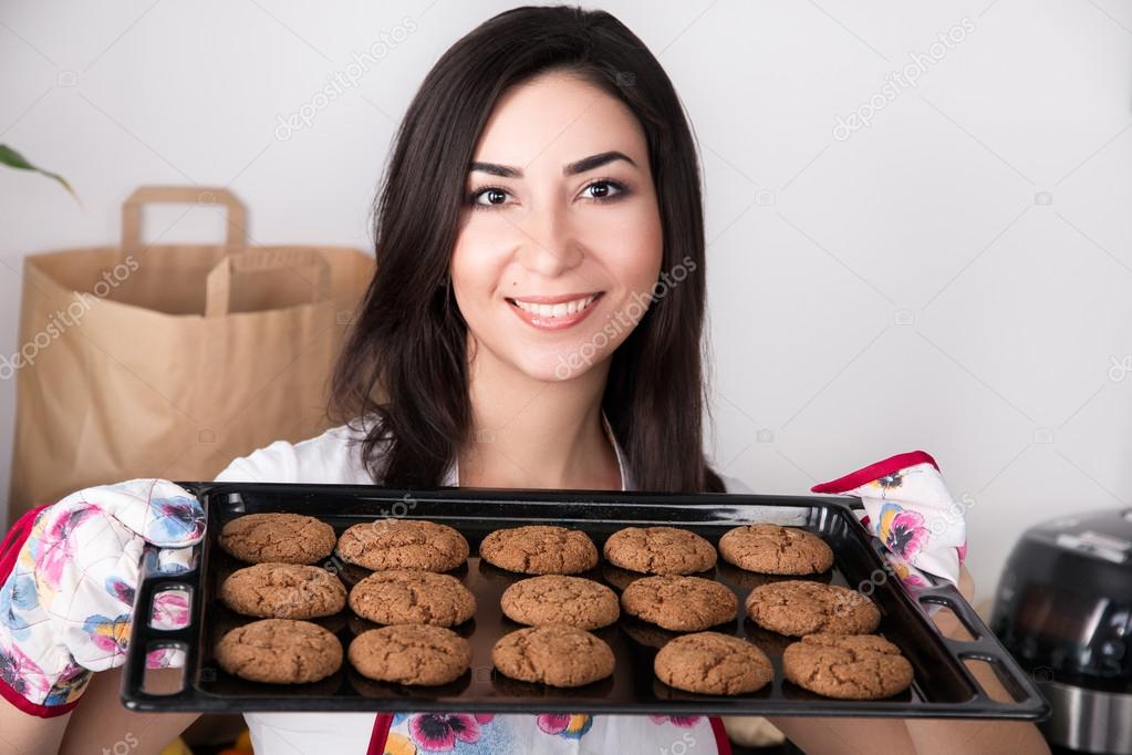 Beautiful woman holding hot roasting pan with cookies