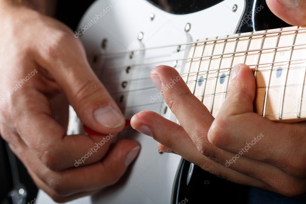 Hands of man playing electric guitar closeup