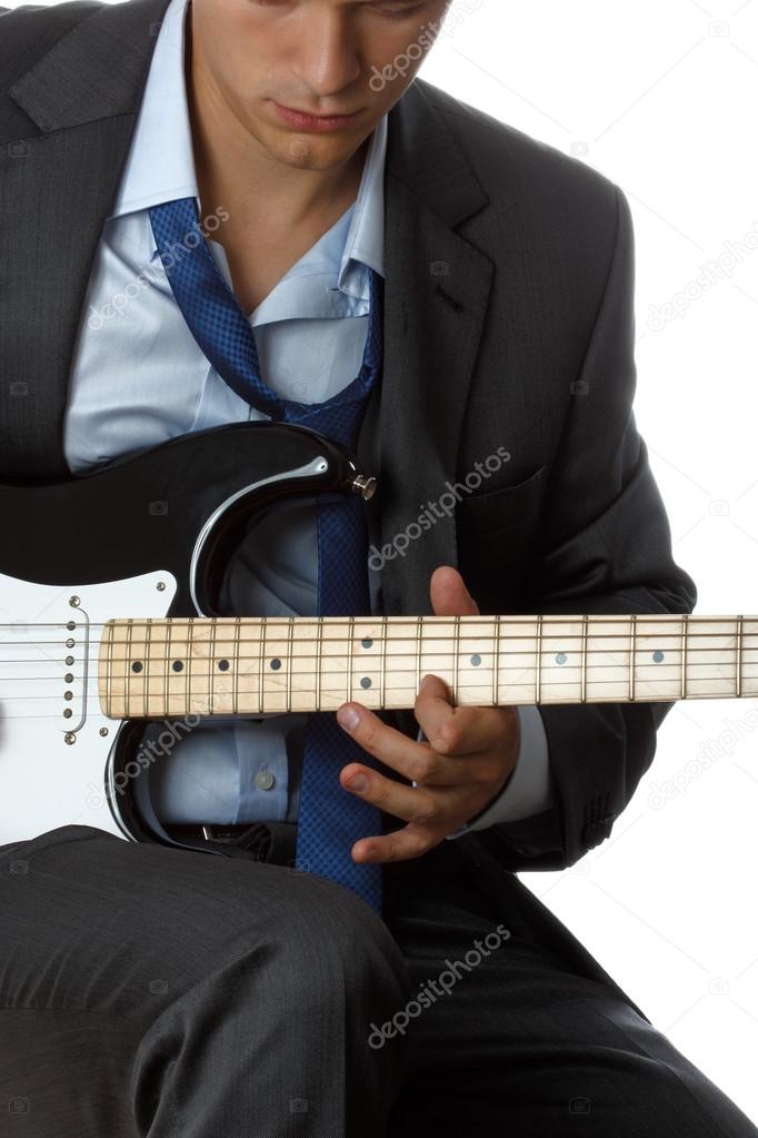 Man in suit and tie playing electric guitar