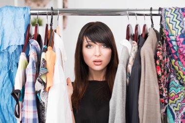 Portrait of young confused woman in front of a wardrobe clipart