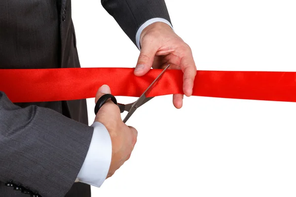 Businessman in suit cutting red ribbon with pair of scissors iso — Stock Photo, Image