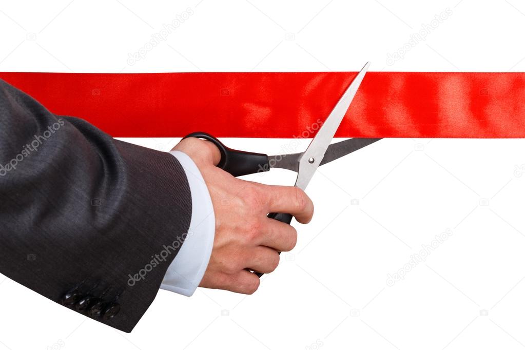 Businessman in suit cutting red ribbon with pair of scissors iso