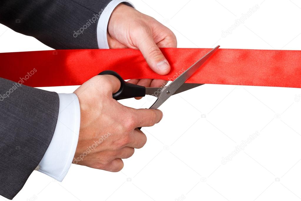 Businessman in suit cutting red ribbon with pair of scissors iso