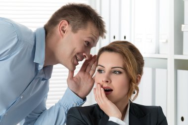 Young man telling gossips to his woman colleague clipart