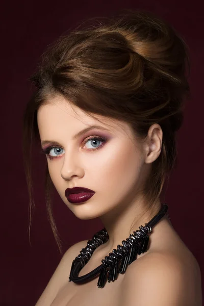 Young pretty girl with vinous lipstick posing at dark red background — Stock Photo, Image