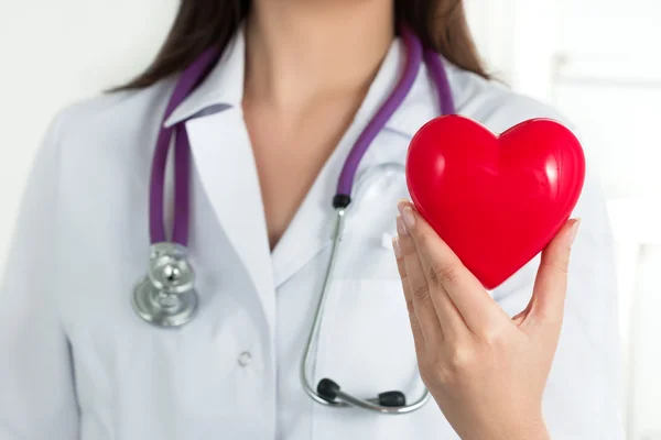 Manos de doctora sosteniendo el corazón rojo — Foto de Stock