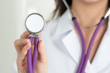 Doctors's hand holding stethoscope's head closeup