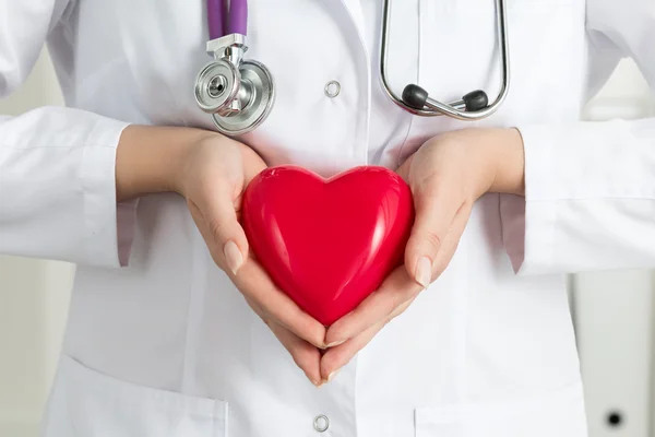 Mãos de médico feminino segurando coração vermelho — Fotografia de Stock