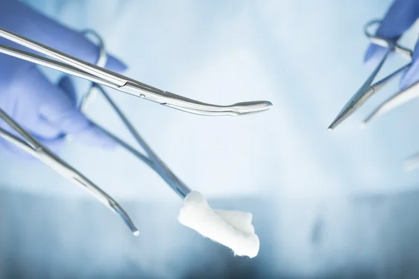 Close-up of doctor's hands holding surgical clamps — Stock Photo, Image