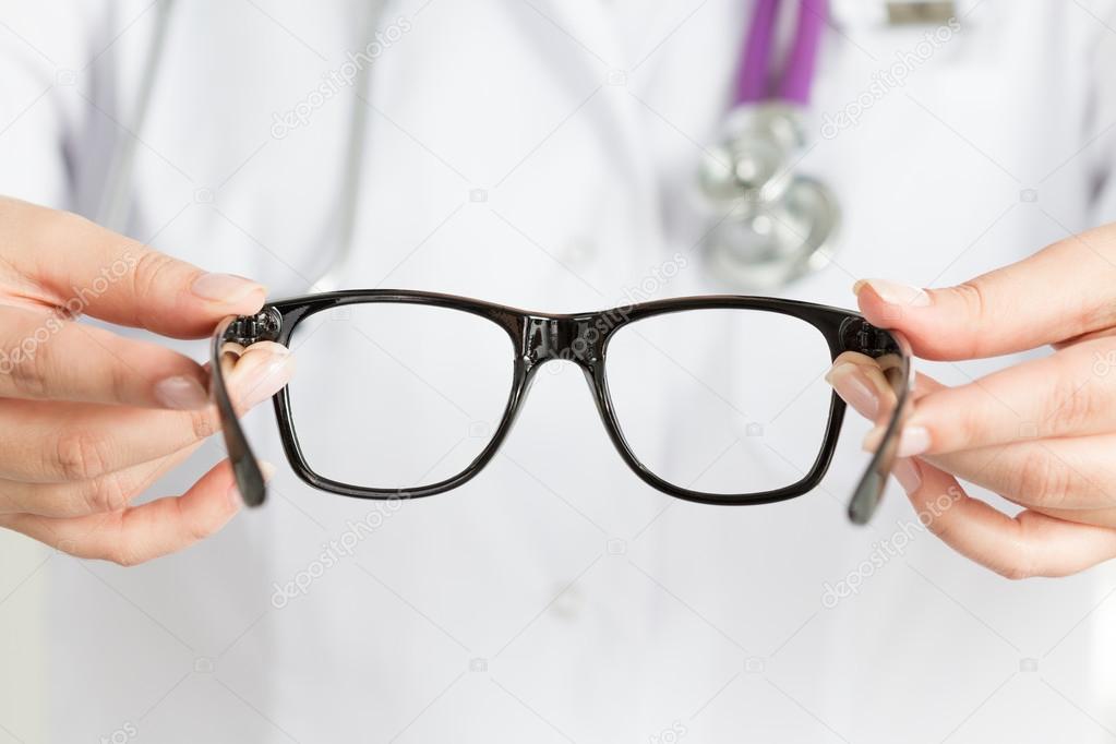 Female oculist doctor's hands giving a pair of black glasses