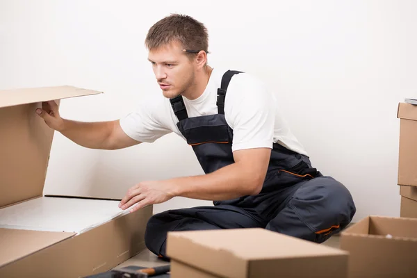 Man unpacking things after relocating — Stock Photo, Image
