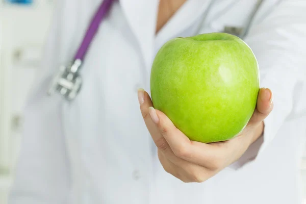 Female doctor hand offering fresh green apple — Stock Photo, Image