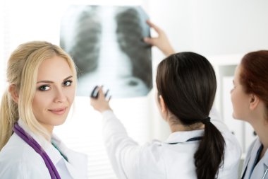 Female medicine doctor with two colleagues looking at x-ray pict