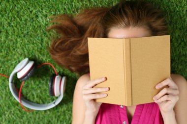 Genç güzel kız bir kitap parkta çim döşeme