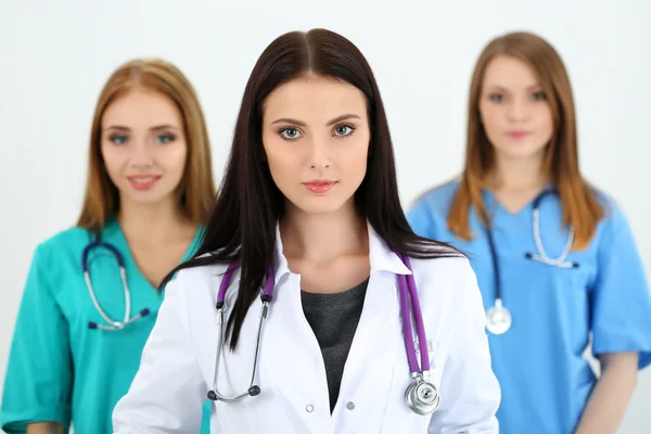 Portrait of young brunette female doctor surrounded by medical team — Stock Photo, Image