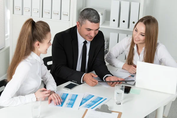 Adult businessman consulting his young female colleagues — Stock fotografie