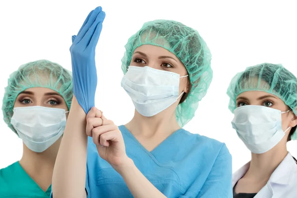 Female doctor in cap and face mask putting on blue protective gl — Stok fotoğraf