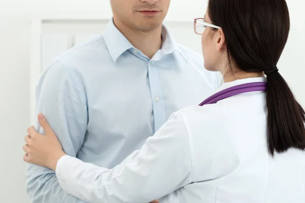 Freundliche Ärztin berührt den Arm eines männlichen Patienten zur Empathie — Stockfoto