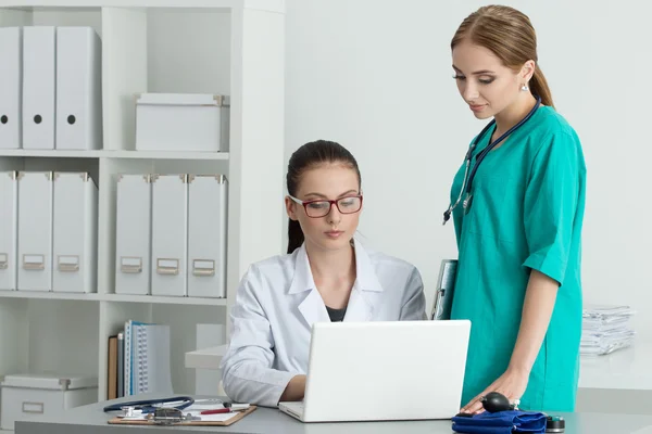 Two beautiful female medicine doctors looking at laptop monitor — Stock Photo, Image