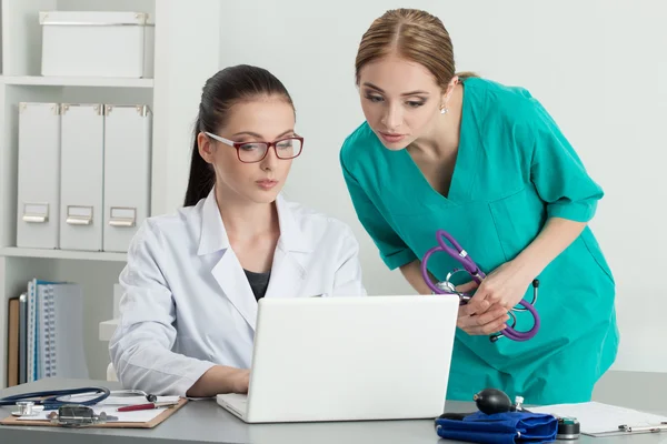 Two beautiful female medicine doctors looking at laptop monitor — Stock Photo, Image