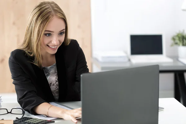 Jovem mulher de negócios sorrindo trabalhando no laptop no escritório — Fotografia de Stock