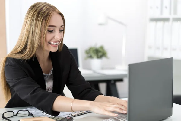 Unga leende affärskvinna arbetar på laptop på kontoret — Stockfoto