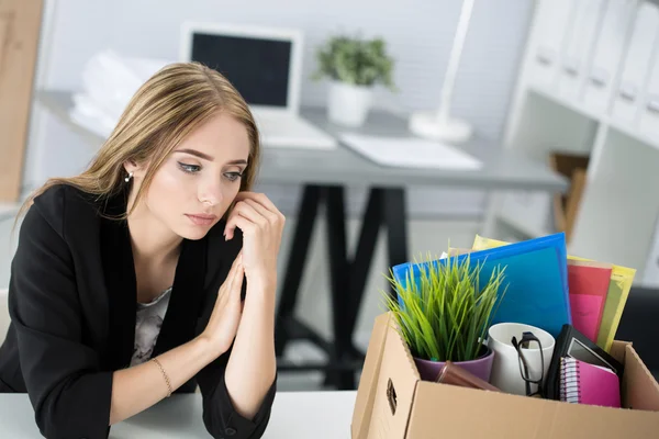 Jonge ontslagen vrouwelijke werknemer in kantoor zit in de buurt van kartonnen doos — Stockfoto