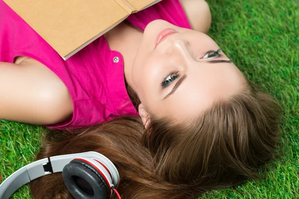 Молодая красивая мечтательная женщина, лежащая на траве в парке — стоковое фото