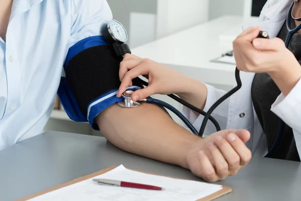 Female medicine doctor measuring blood pressure to patient — Stock Photo, Image