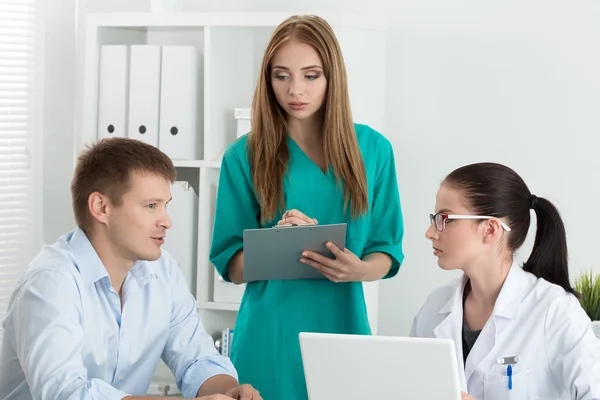 Médico femenino con su colega consultando al paciente —  Fotos de Stock