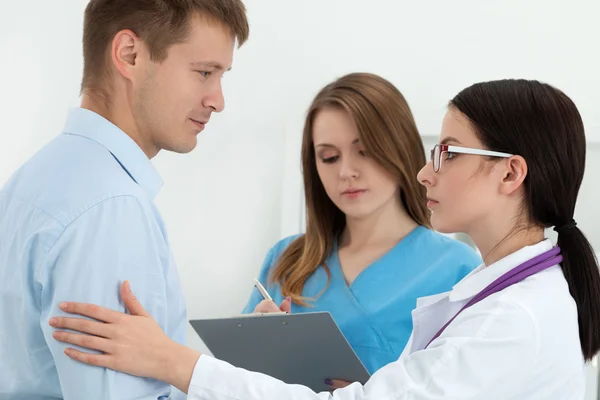 Amistosa doctora tocando el brazo del paciente masculino para alentar —  Fotos de Stock