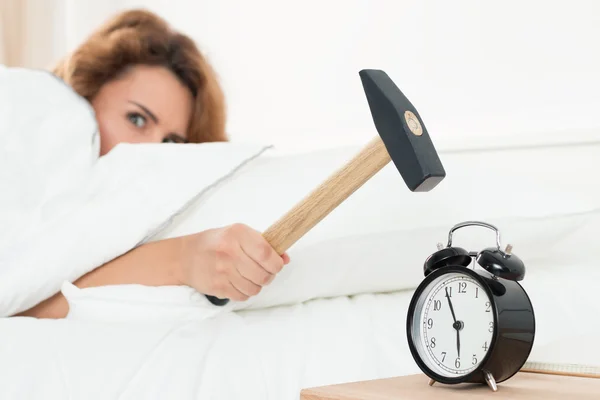 Young woman trying to break the alarm with hammer — Stockfoto
