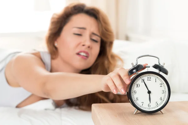 Junge schläfrige Frau versucht, den Wecker auszuschalten — Stockfoto