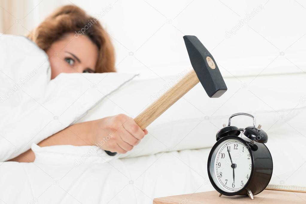 Young woman trying to break the alarm with hammer