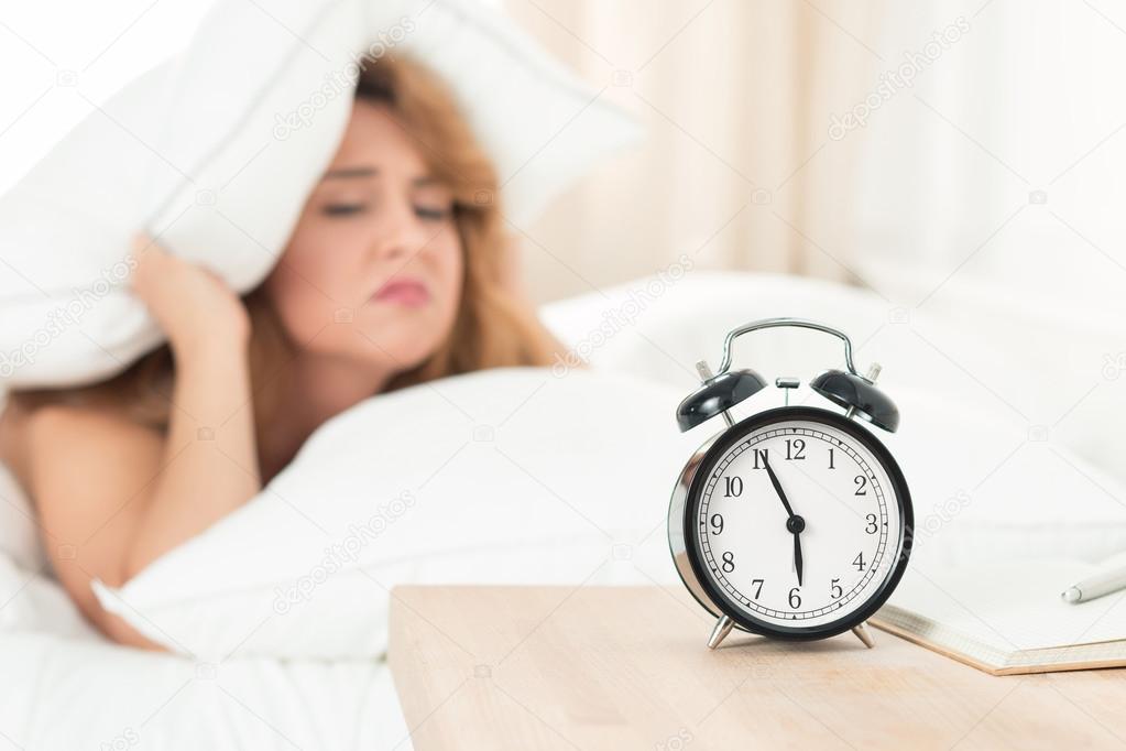 Young beautiful woman hates waking up early in the morning