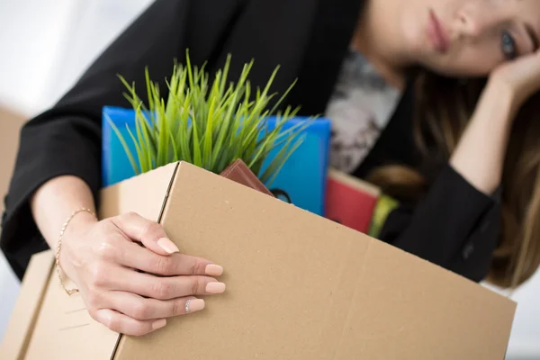 Jonge ontslagen vrouwelijke werknemer in kantoor houden kartonnen doos met — Stockfoto