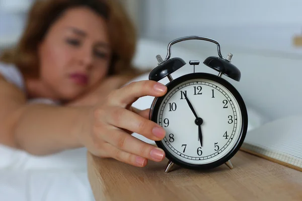 Unga sömnig kvinna försöker stänga av väckarklockan — Stockfoto