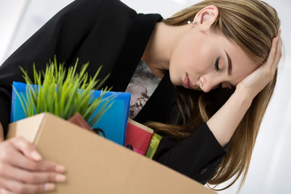 Young dismissed female worker in office holding carton box with — Stock Photo, Image