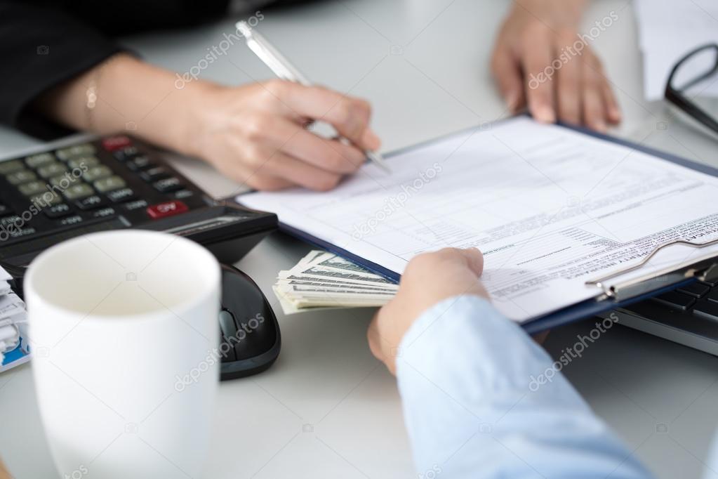 Woman signing documents for a batch of hundred dollar bills