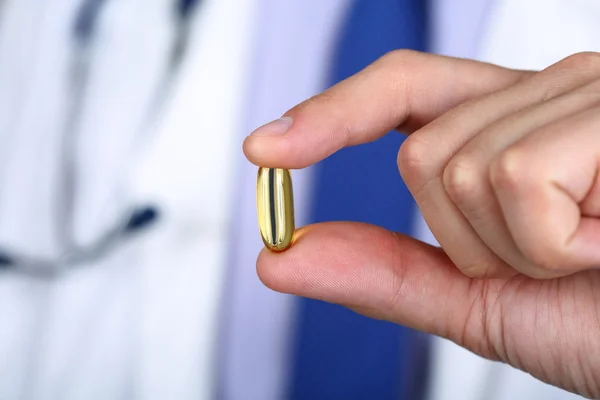 Close-up of doctor fingers holding fish oil capsule — Stock Photo, Image