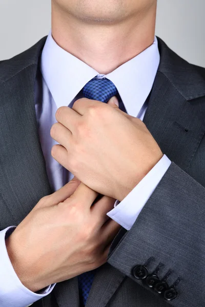 Geschäftsmann im grauen Anzug bindet die Krawatte — Stockfoto