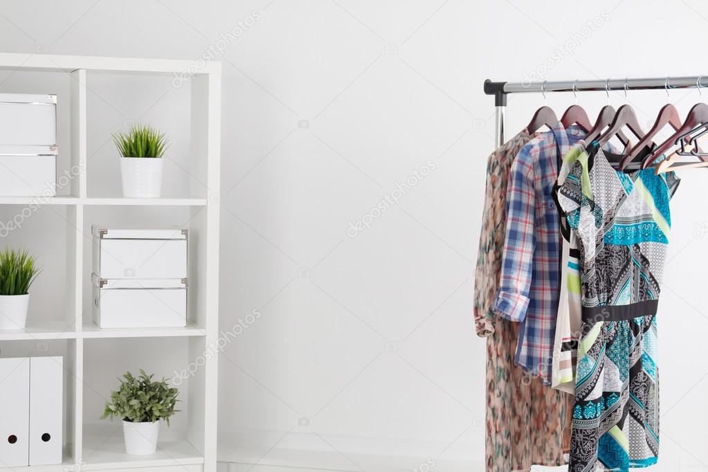 Colorful clothes on hanger in white room