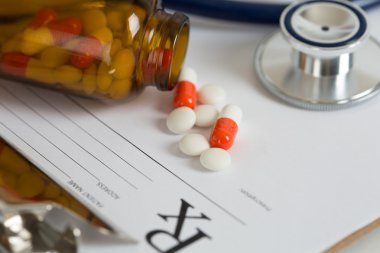Bir masanın üzerinde yatan bir stetoskop baş ve hapları reçete formu