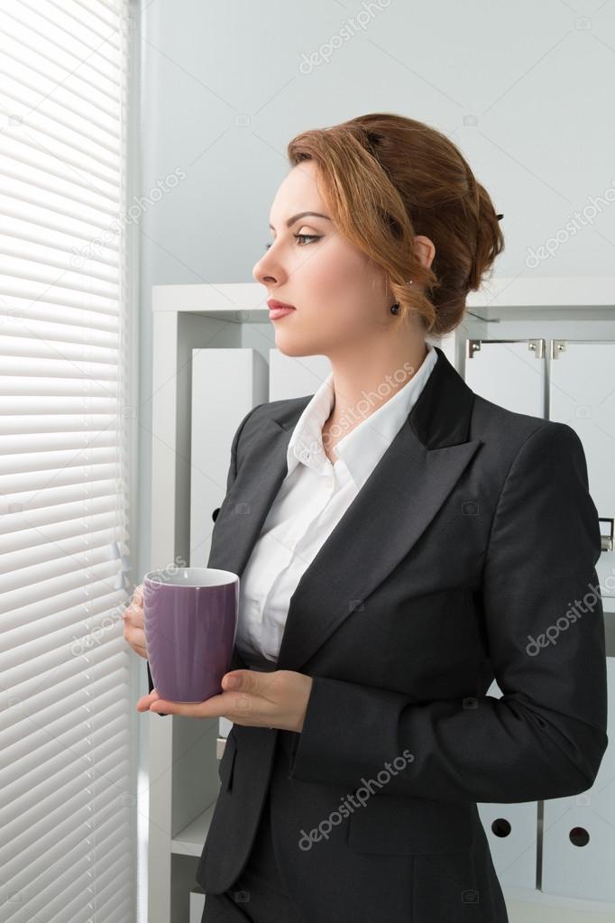 business woman standing near the window and looking outside with