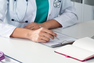 Close-up shot of female medical doctor's hands filling paient re