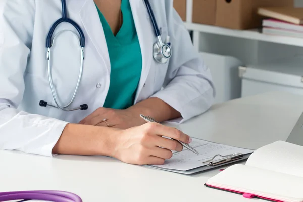 Primer plano de las manos del médico femenino llenando paient re — Foto de Stock