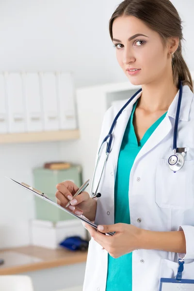 Женщина-врач заполняет регистрационную форму пациента — стоковое фото