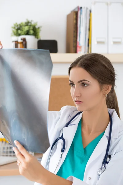 Young female doctor looking at lungs x-ray image — Stock Photo, Image