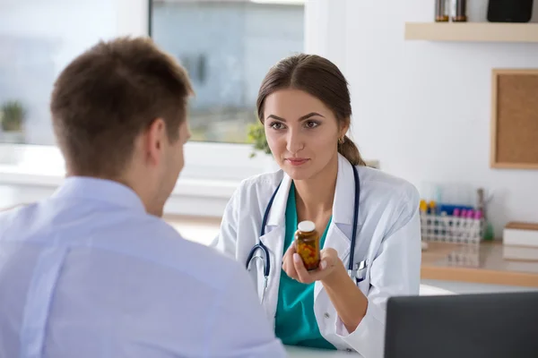Médico de medicina femenino recetando pastillas a su paciente masculino —  Fotos de Stock