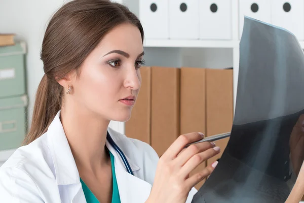 Young female doctor looking at lungs x-ray image — Stock Photo, Image